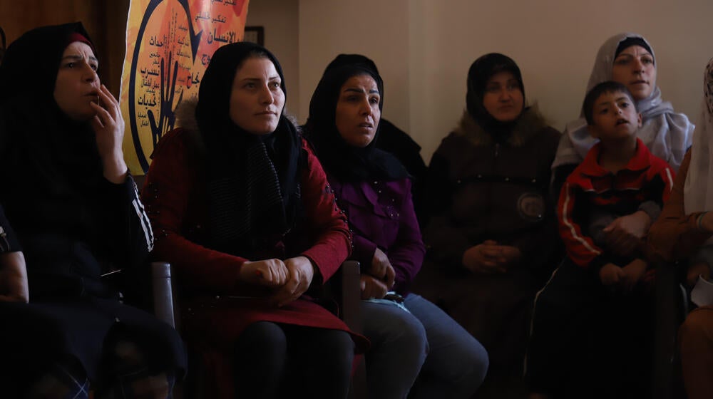 مجموعة من النساء وطفل صغير يجلسون داخل مركز الحسينية في قرية الأشرفية بريف حمص