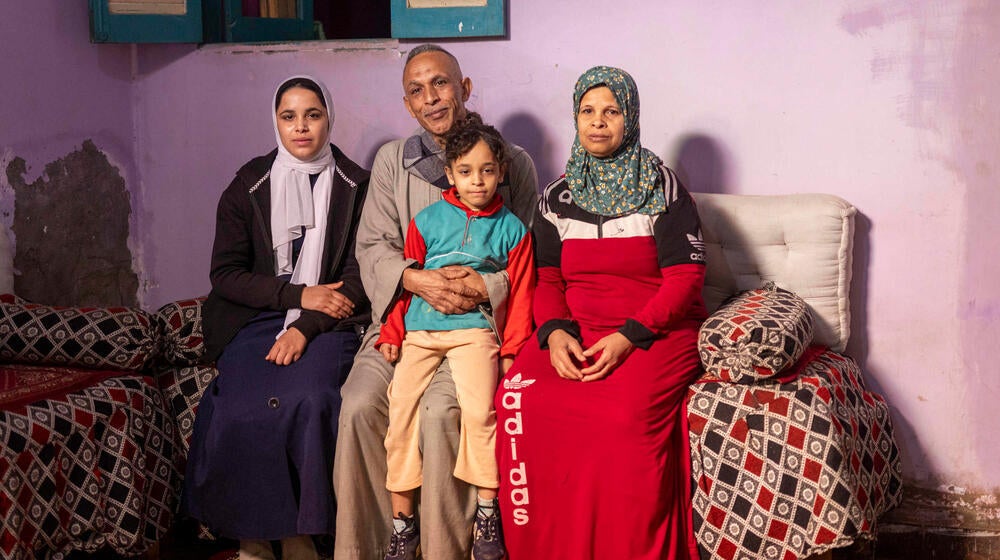 An Egyptian family of four sit together on a sofa. 