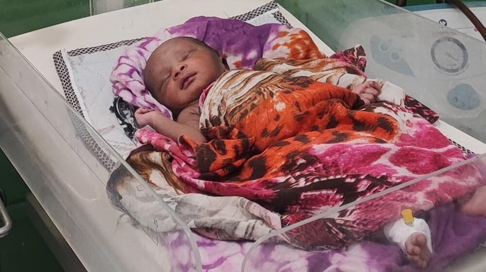 Un recién nacido envuelto en un pañuelo de colores en una cuna de hospital